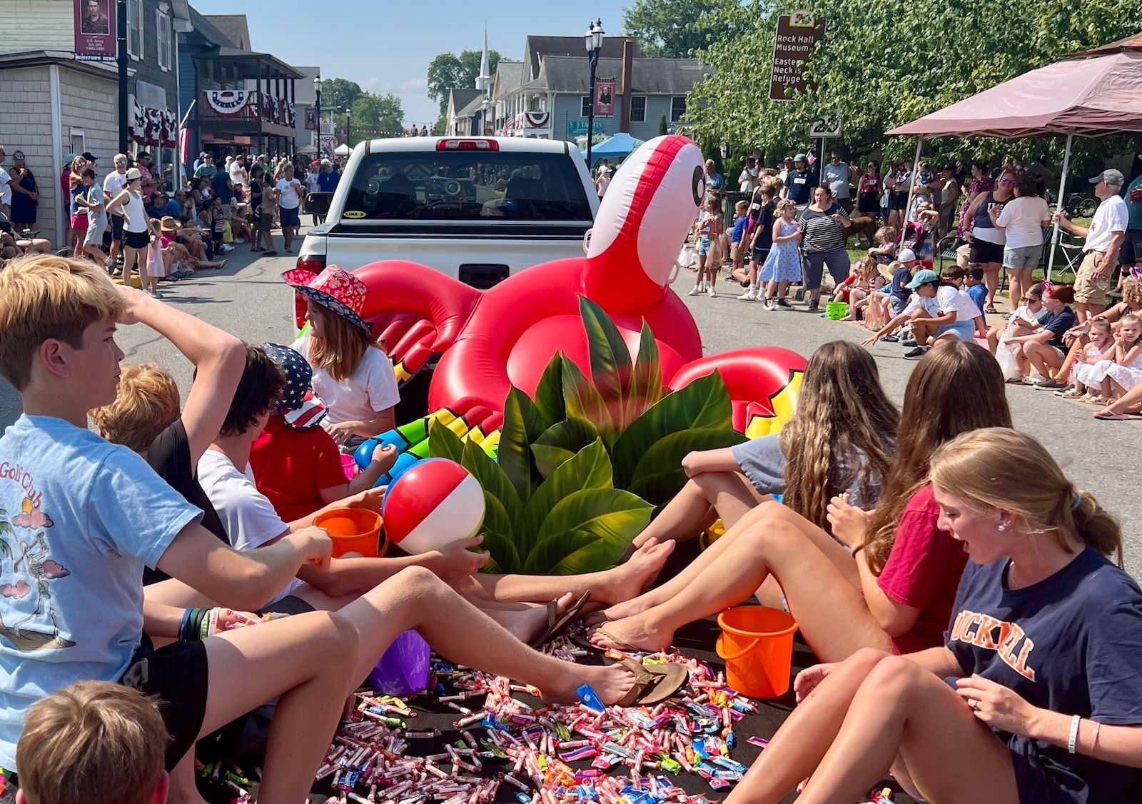 Group of children ride on a Fourth of July parade float down a small town's Main Street