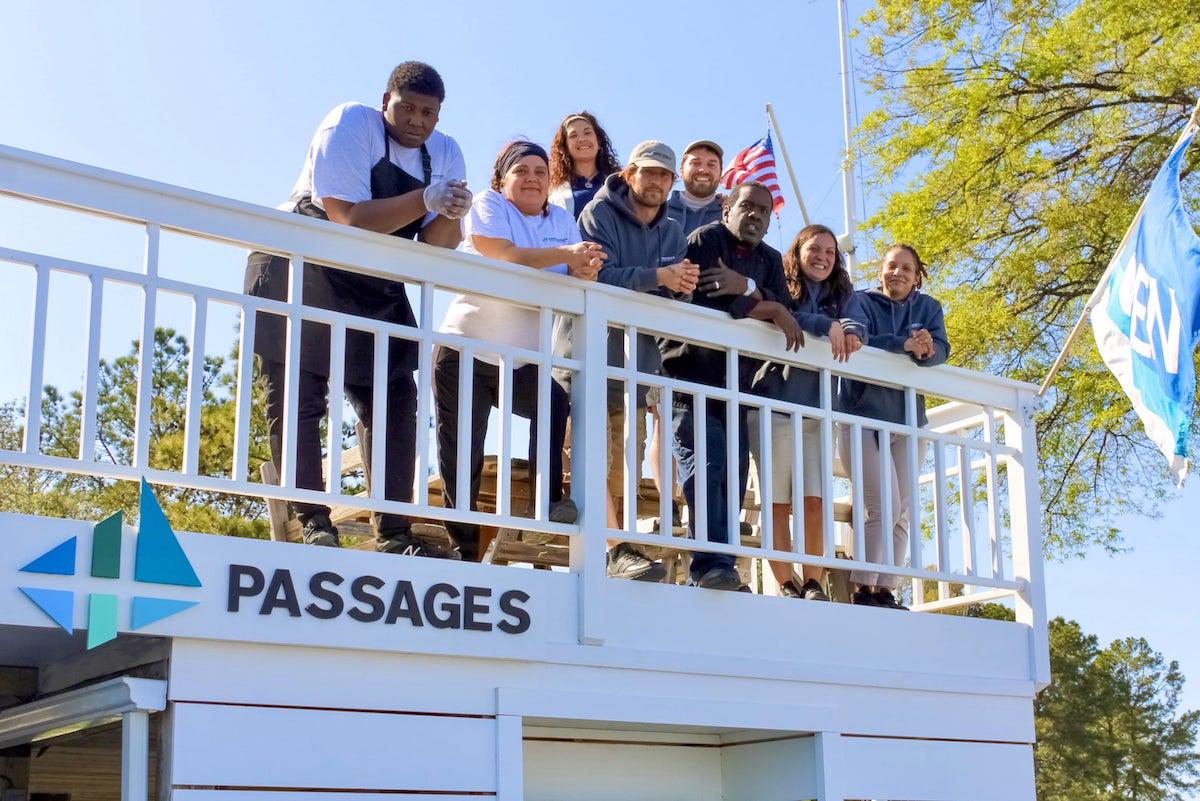 Group of employees pictured outside on a sunny day along deck railing