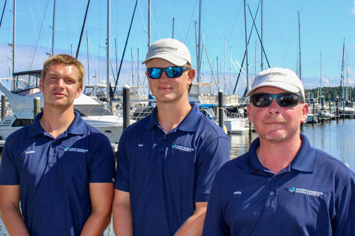 Group of employees pictured outside on a sunny summer day with boats in the background