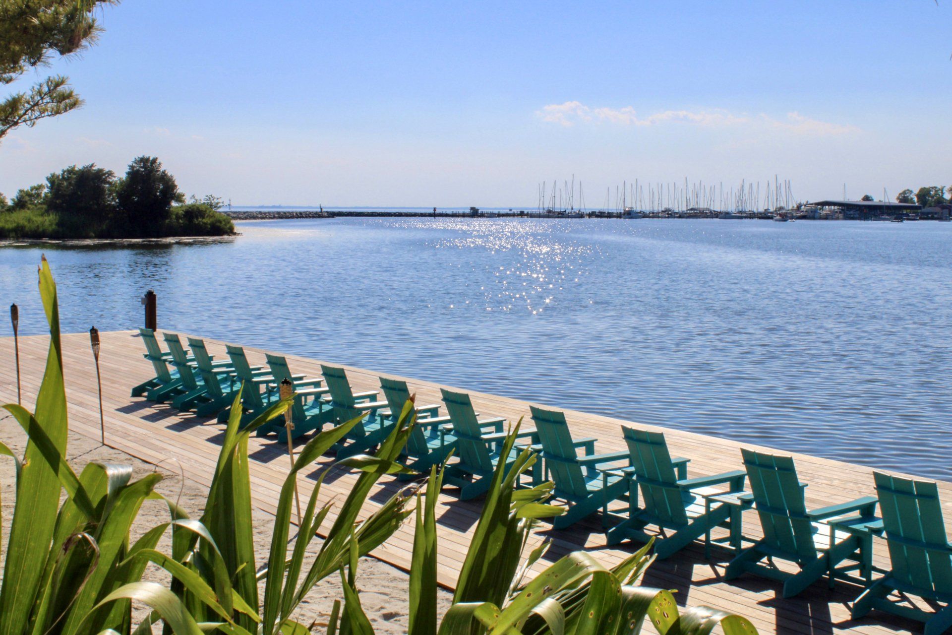 Large waterfront deck with teal chairs and tables in single line