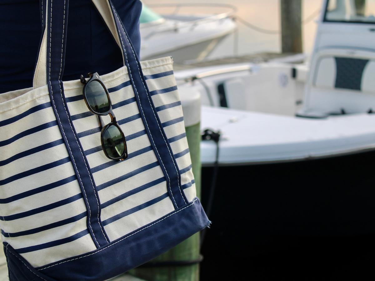 Striped canvas bag with sunglasses and boat in background