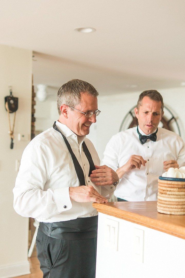 Groomsmen prepare for wedding in a white room