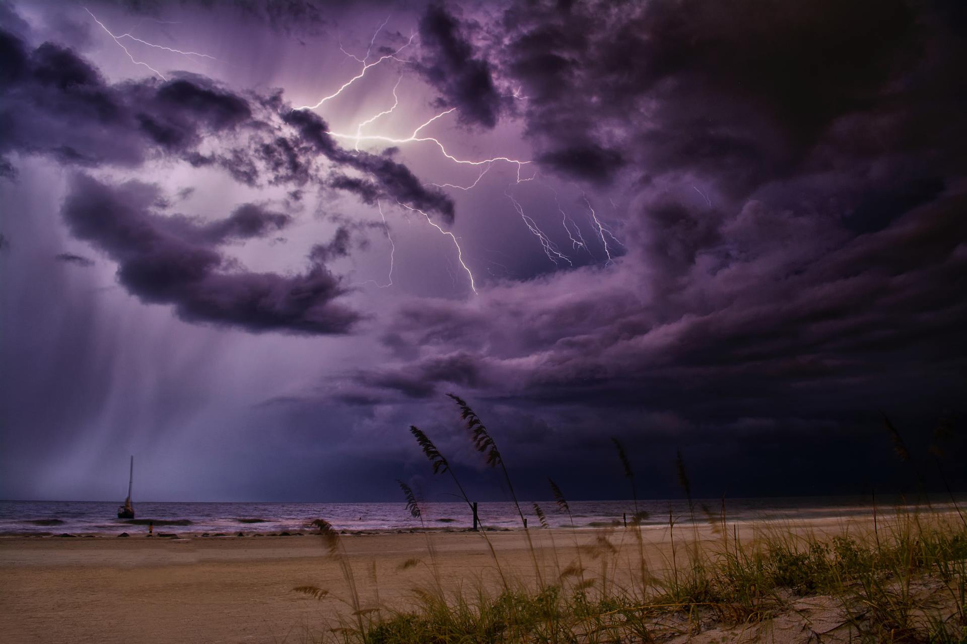 Thunderstorm and lightning approach a beach and boat