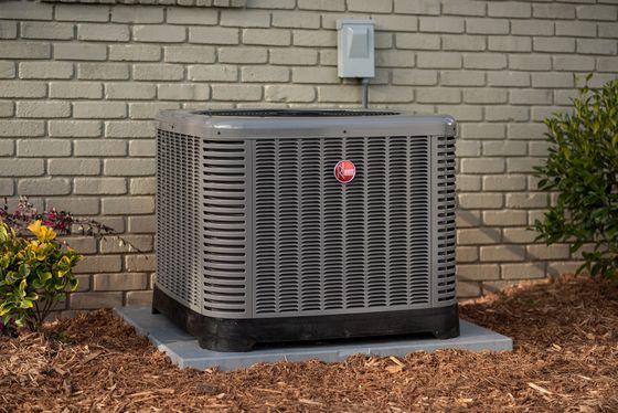 A man is working on an air conditioner outside of a building.