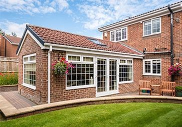 A brick house with a white roof and a patio in front of it.