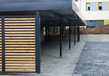 A carport with a wooden fence in front of a building.