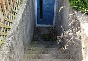 A set of stairs leading up to a blue door in a basement.