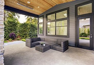 A covered patio with a couch , chairs , and a table.
