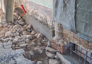 A pile of rocks is sitting on the ground next to a brick wall.