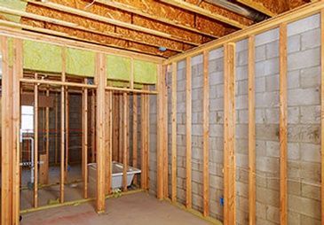 A room in a house under construction with wooden beams and brick walls.