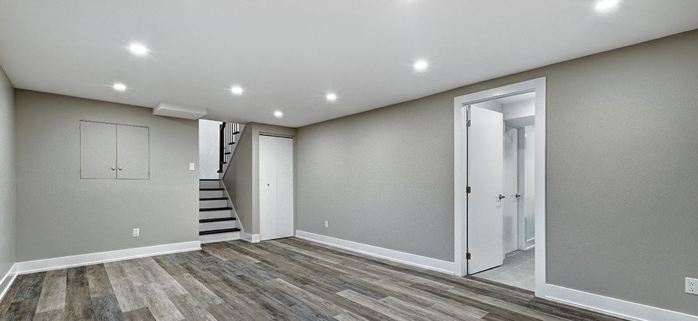 An empty basement with hardwood floors and stairs.