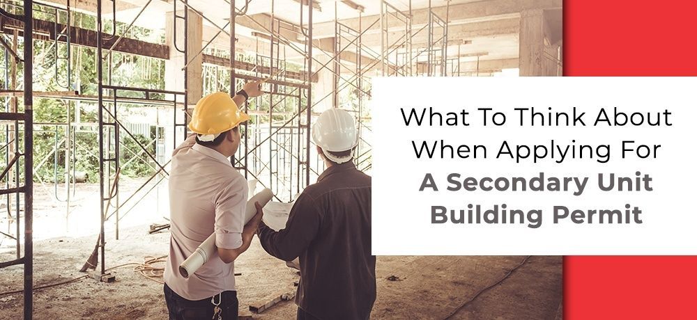 Two construction workers are standing in a building under construction.