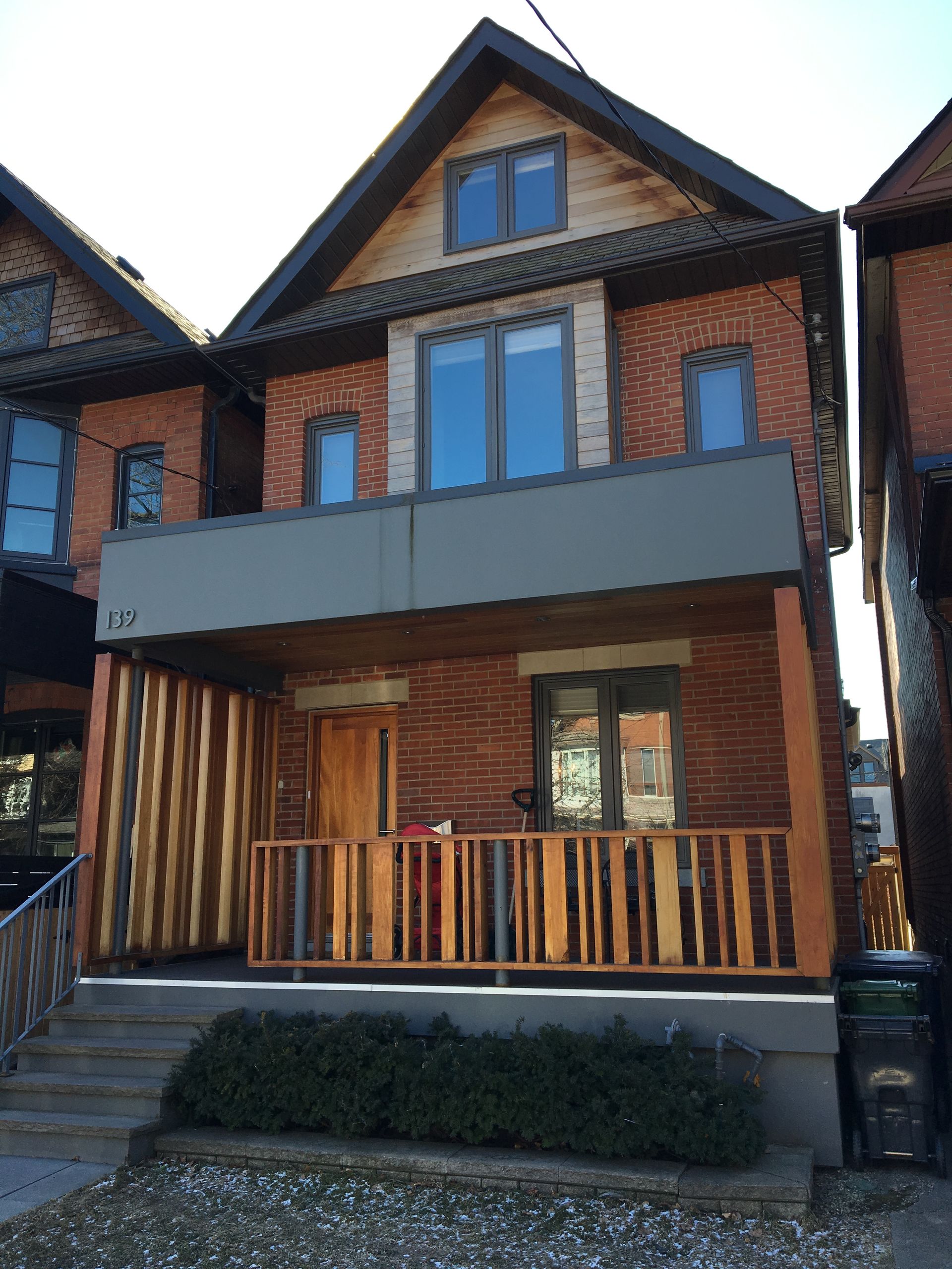 A brick house with a wooden porch and stairs