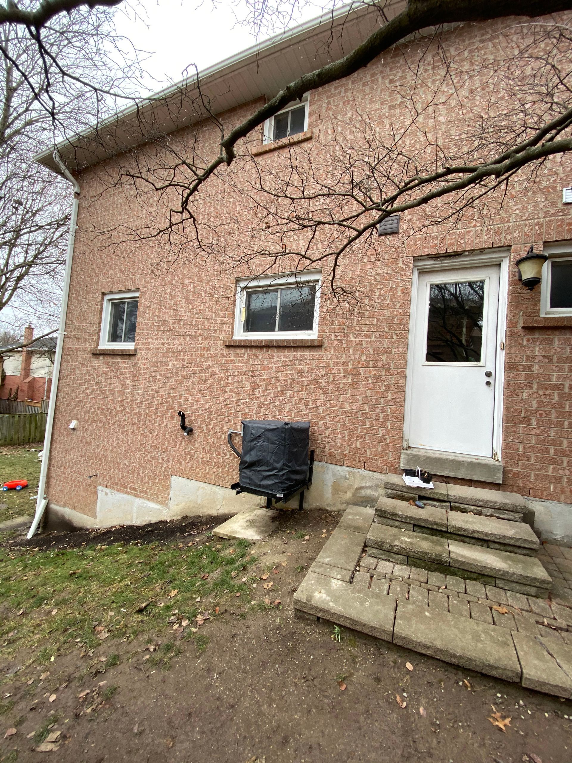 A brick house with a white door and stairs in the backyard.