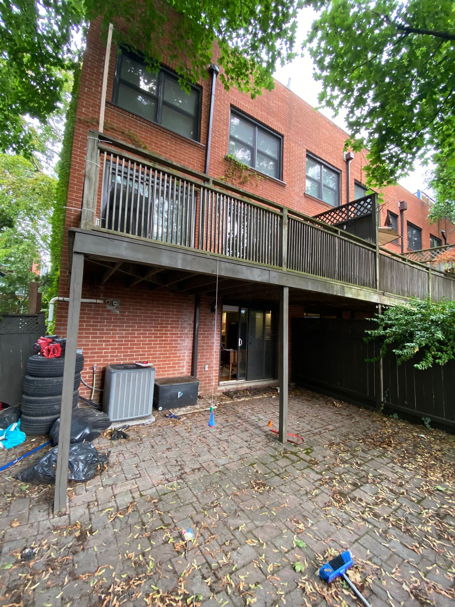 The backyard of a brick house with a wooden deck.