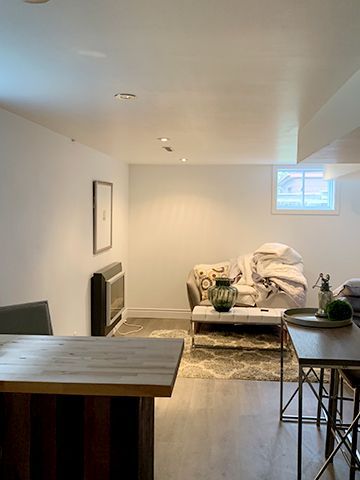 A living room with a couch , table , chairs and a window.