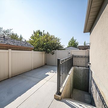 A backyard with a fence and stairs leading to a basement