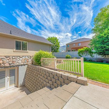 A house with a stone wall and a fence in the backyard.