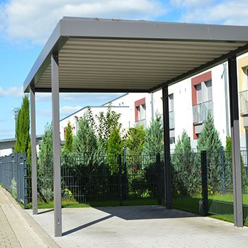 There is a carport with a canopy over it in front of a building.