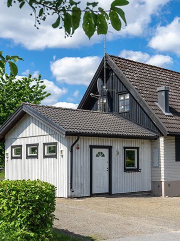 A white house with a black roof has a garage attached to it