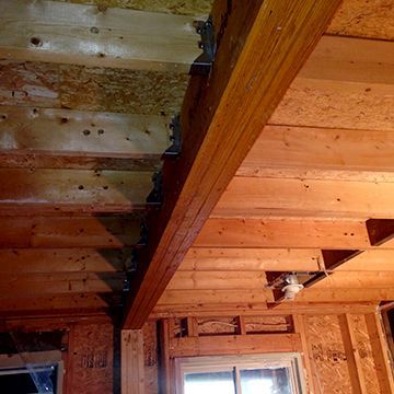 A wooden ceiling in a house with a window and a ceiling fan.