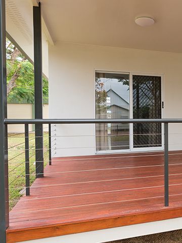 A wooden deck with a metal railing and a sliding glass door.