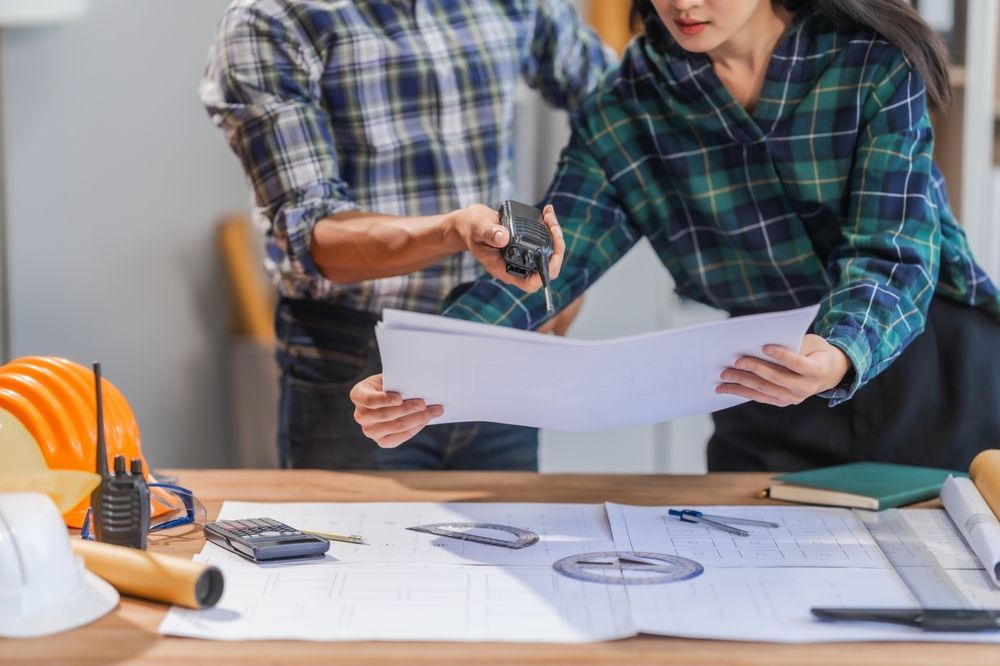 A man and a woman are sitting at a table looking at a blueprint.