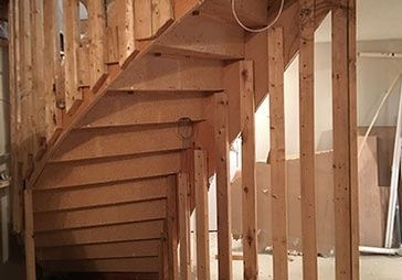 A wooden staircase is being built in a room.
