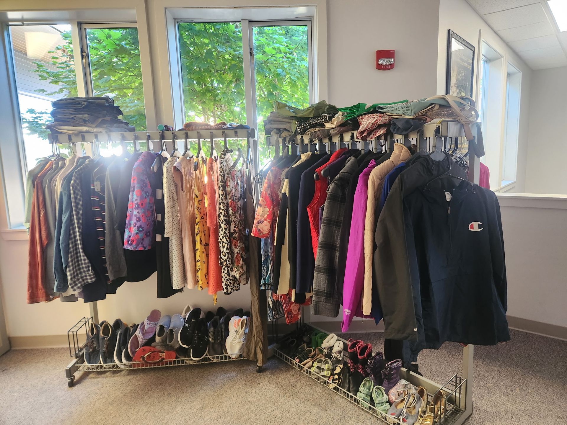 A bunch of clothes are hanging on racks in one of the church's hallway.