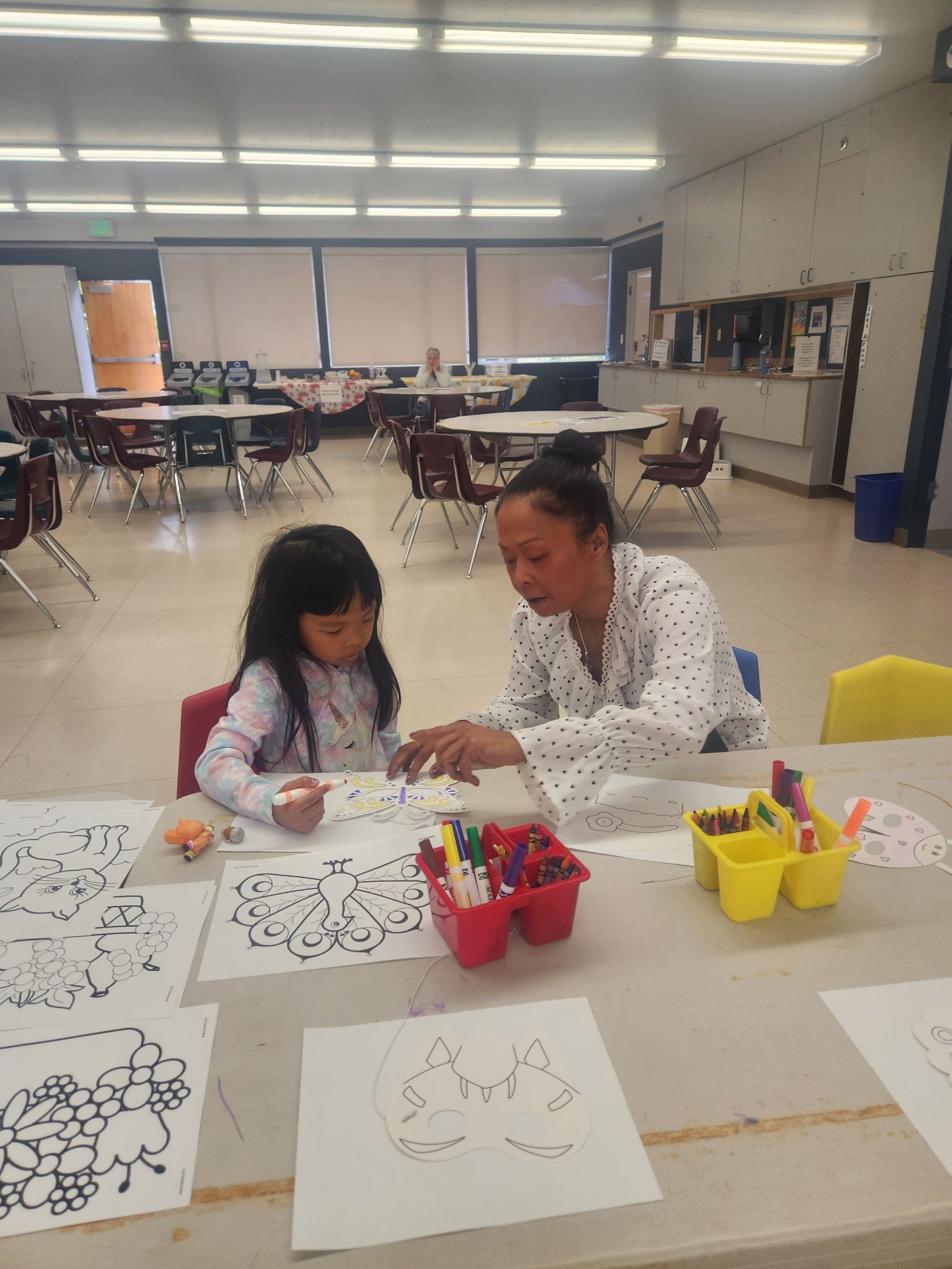 A woman and a little girl are sitting at a table in a room.