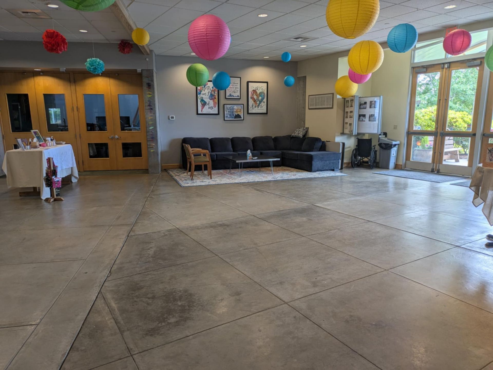 A man is standing in the church's large foyer, with smooth concrete flooring.