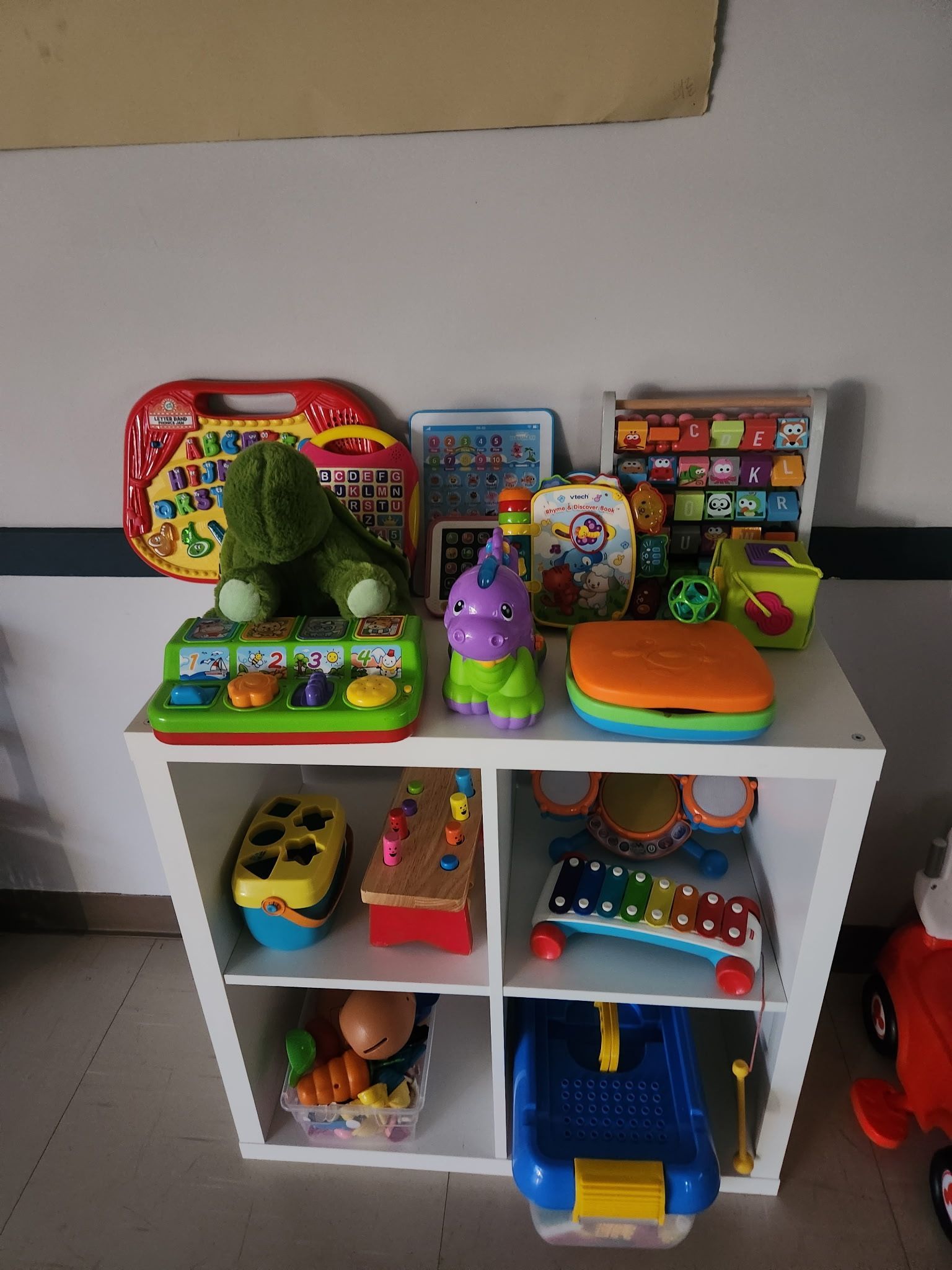 A shelf filled with lots of children 's toys and books in the church's lunchroom.