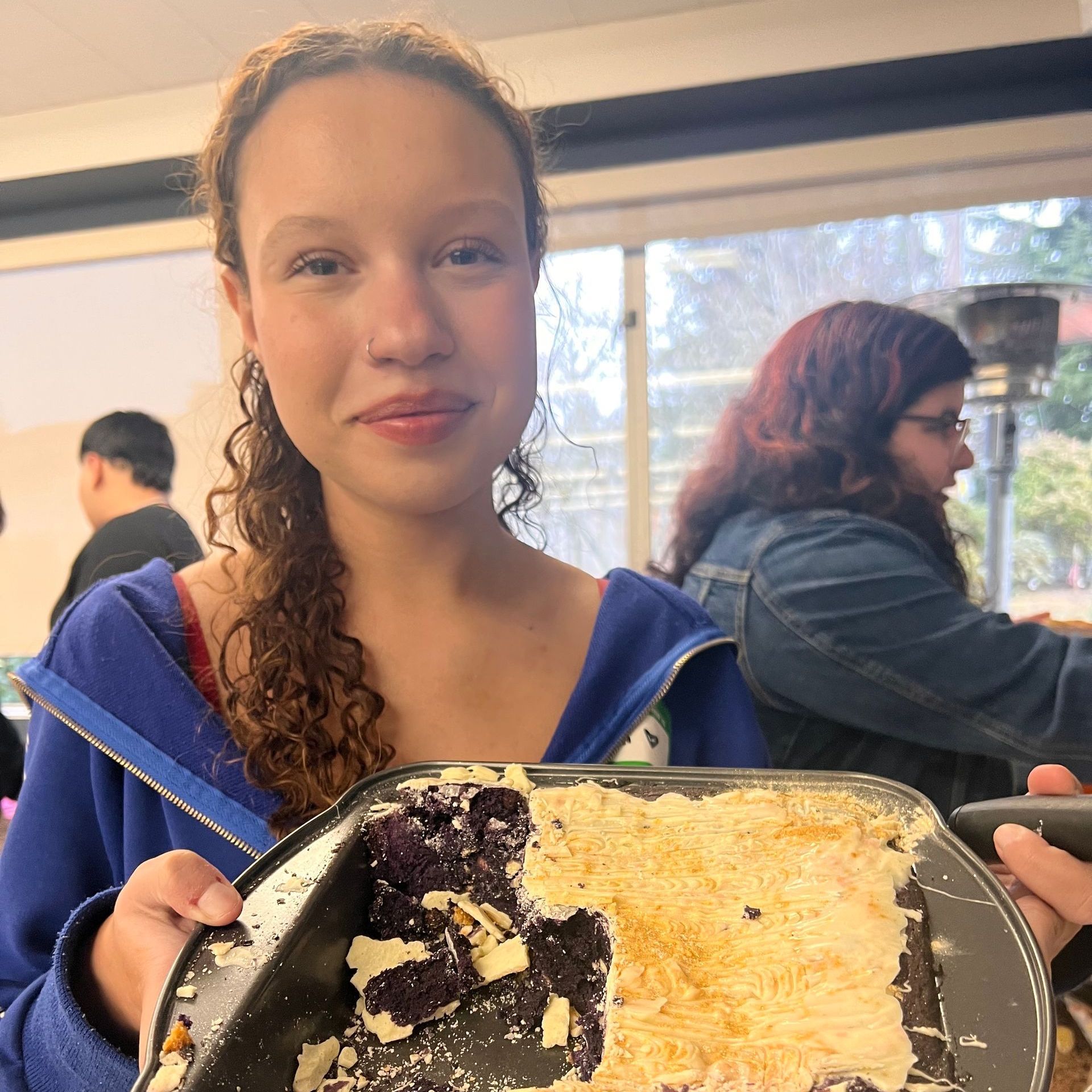 A woman in a blue jacket is holding a plate of food