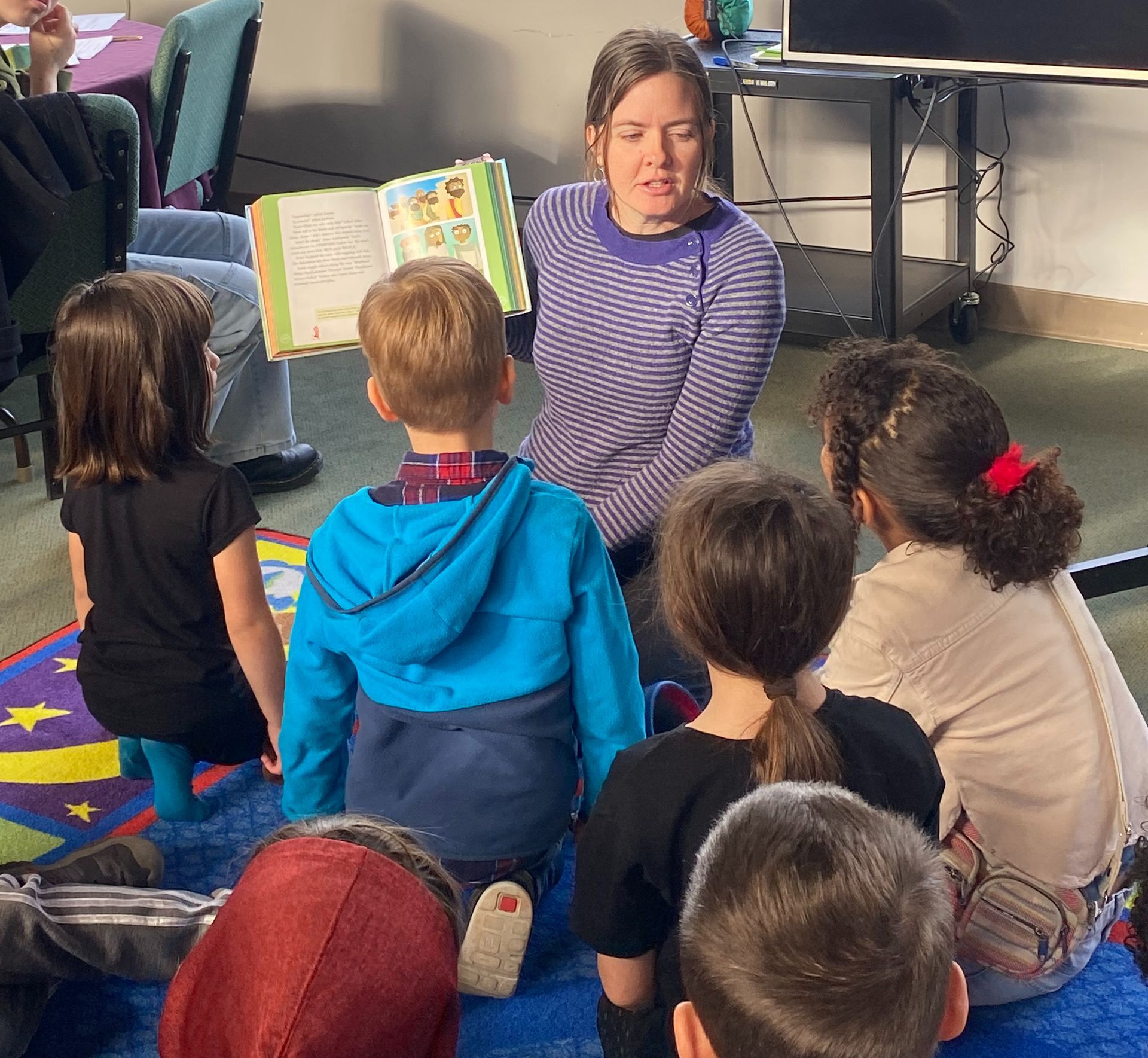 A woman is reading a book to a group of children