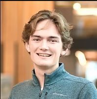 A young man in a blue jacket is smiling for the camera.