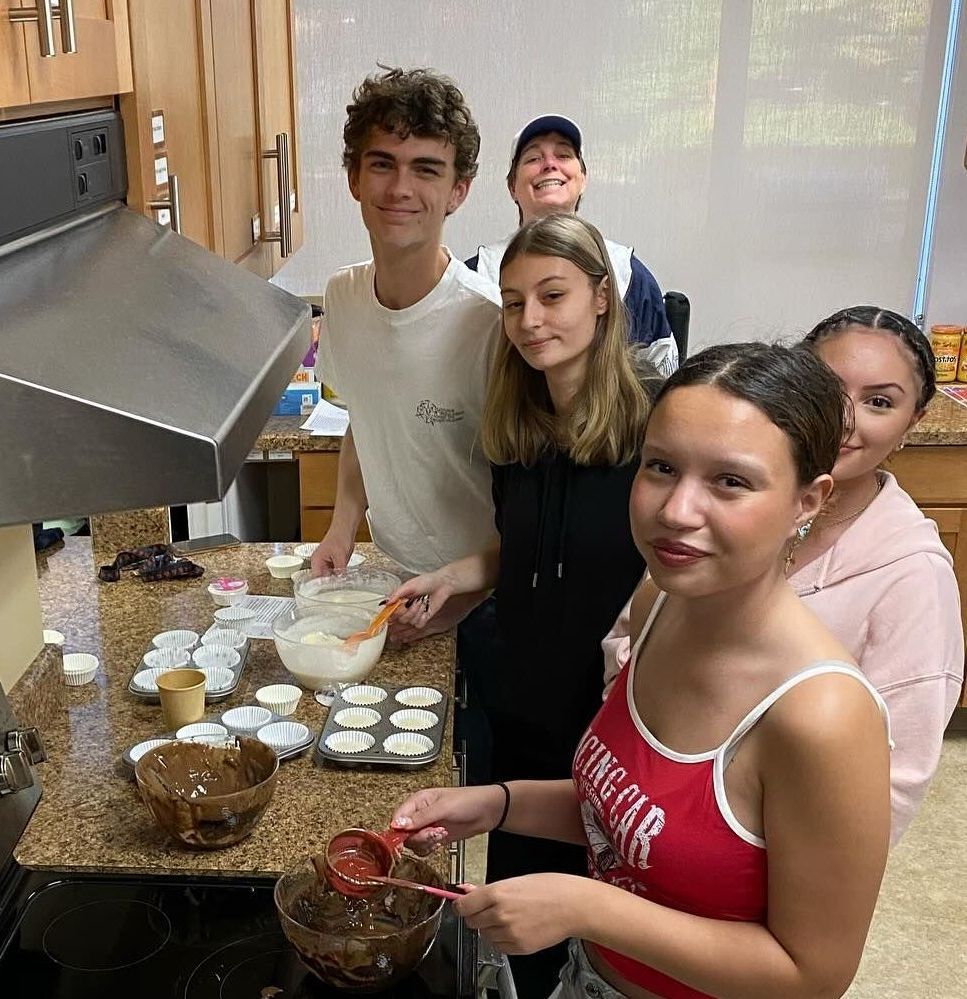 A group of people are standing in a kitchen preparing food.