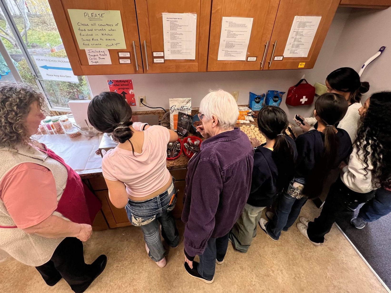 A group of people are standing around a counter in a kitchen