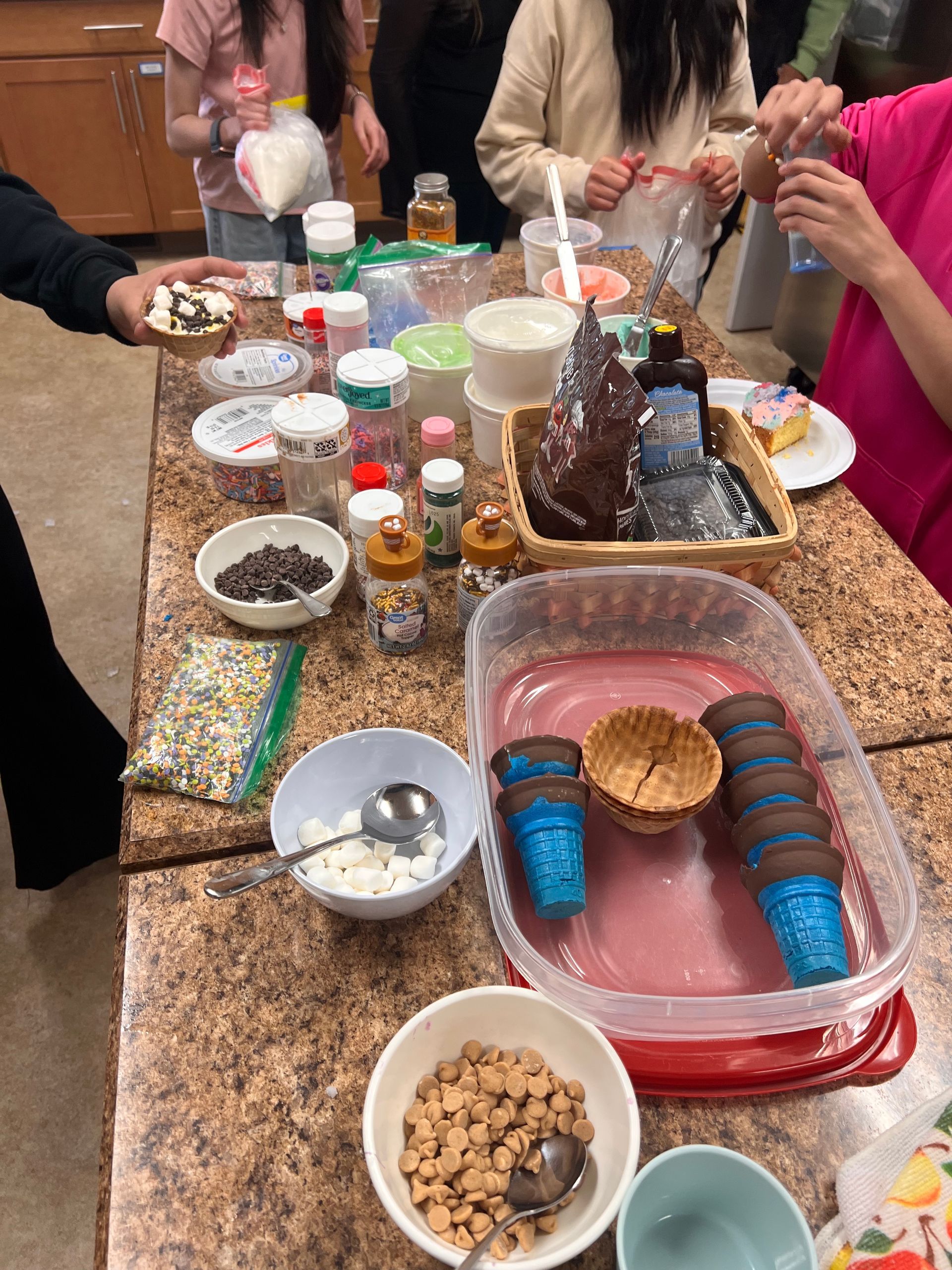 A table with bowls of food and ice cream cones.