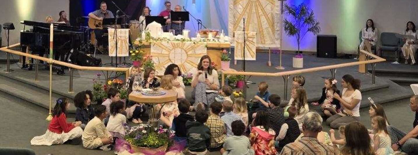 A group of children are sitting on the floor in a church.