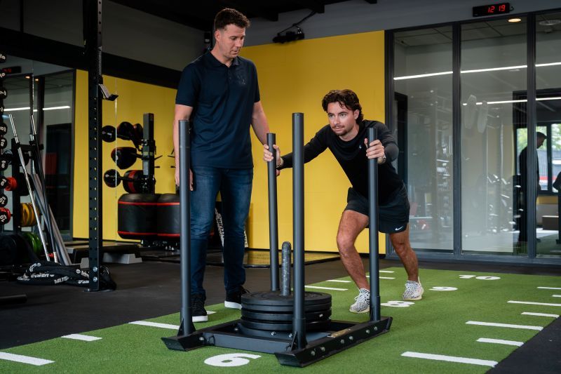 Medewerker van Revital die een deelnemer van Strong en Steady begeleid tijdens een oefening