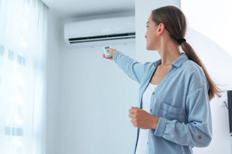 a young woman adjusts the AC temperature