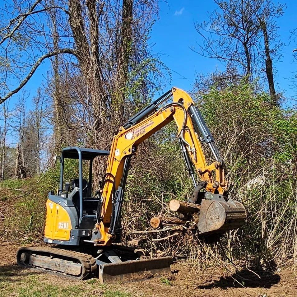 A small excavator is sitting in the middle of a field.