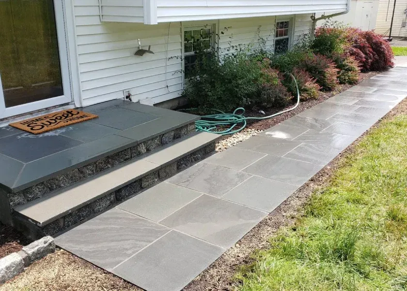 A concrete walkway leading to the front door of a house.