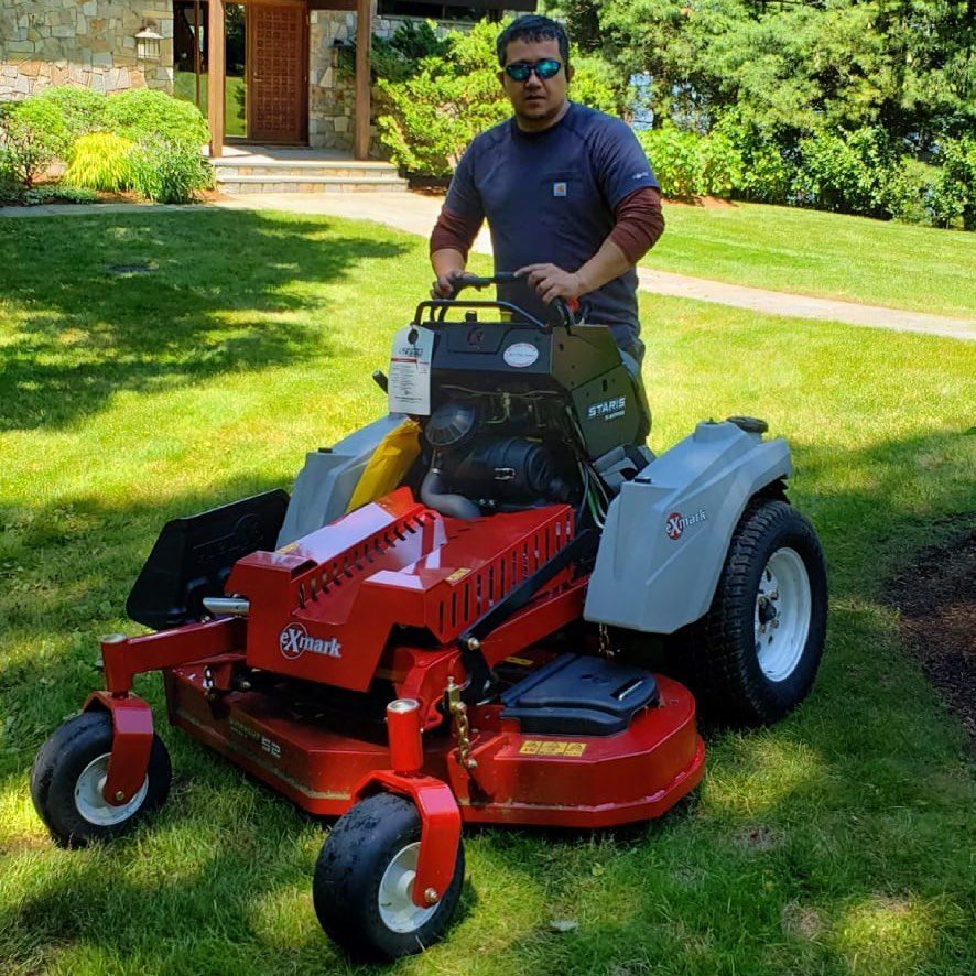 A man is riding a lawn mower in a lush green yard.