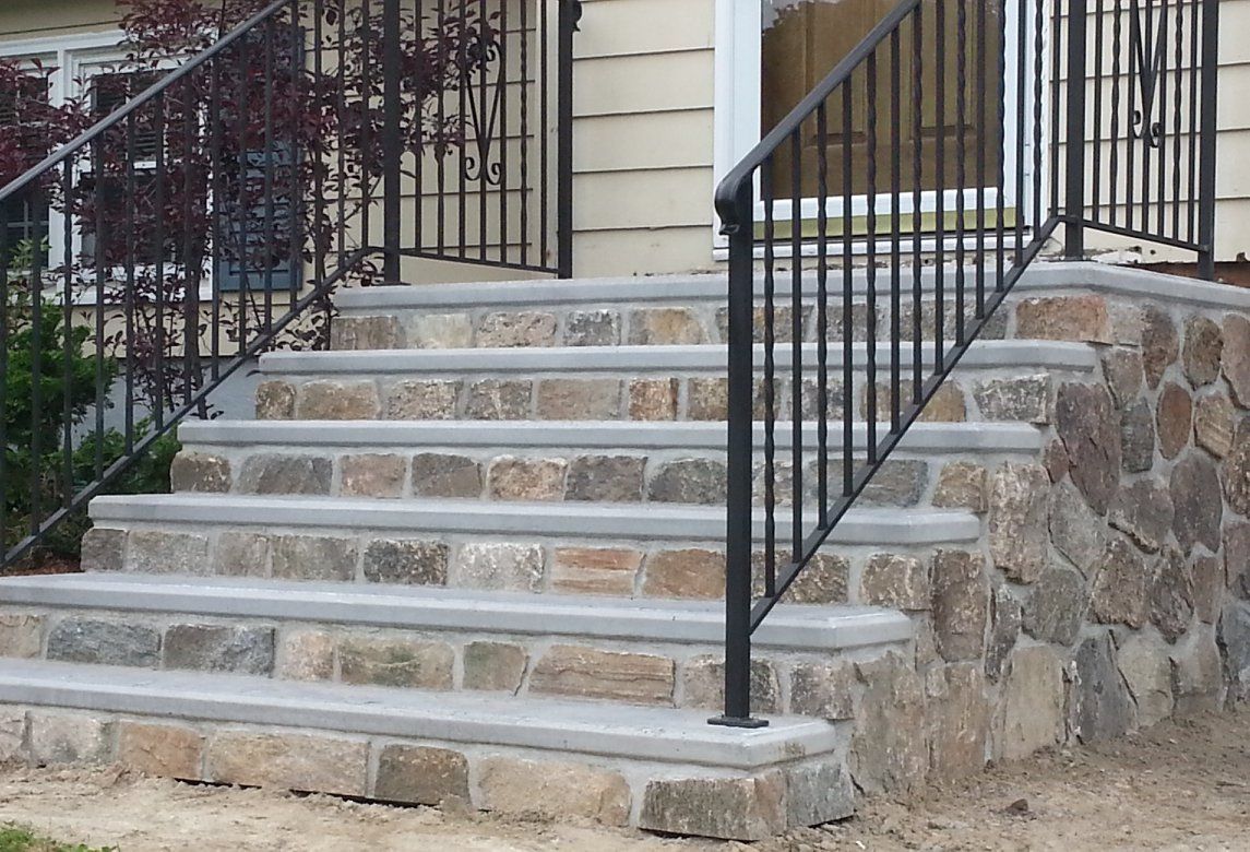 A set of stone stairs with a metal railing