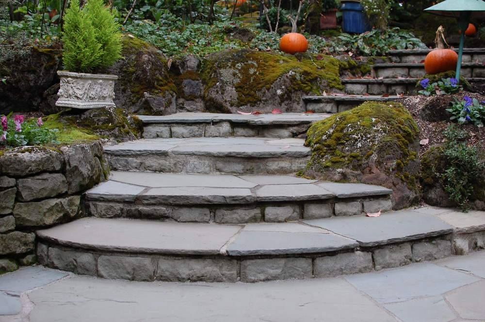 A stone staircase in a garden with pumpkins in the background