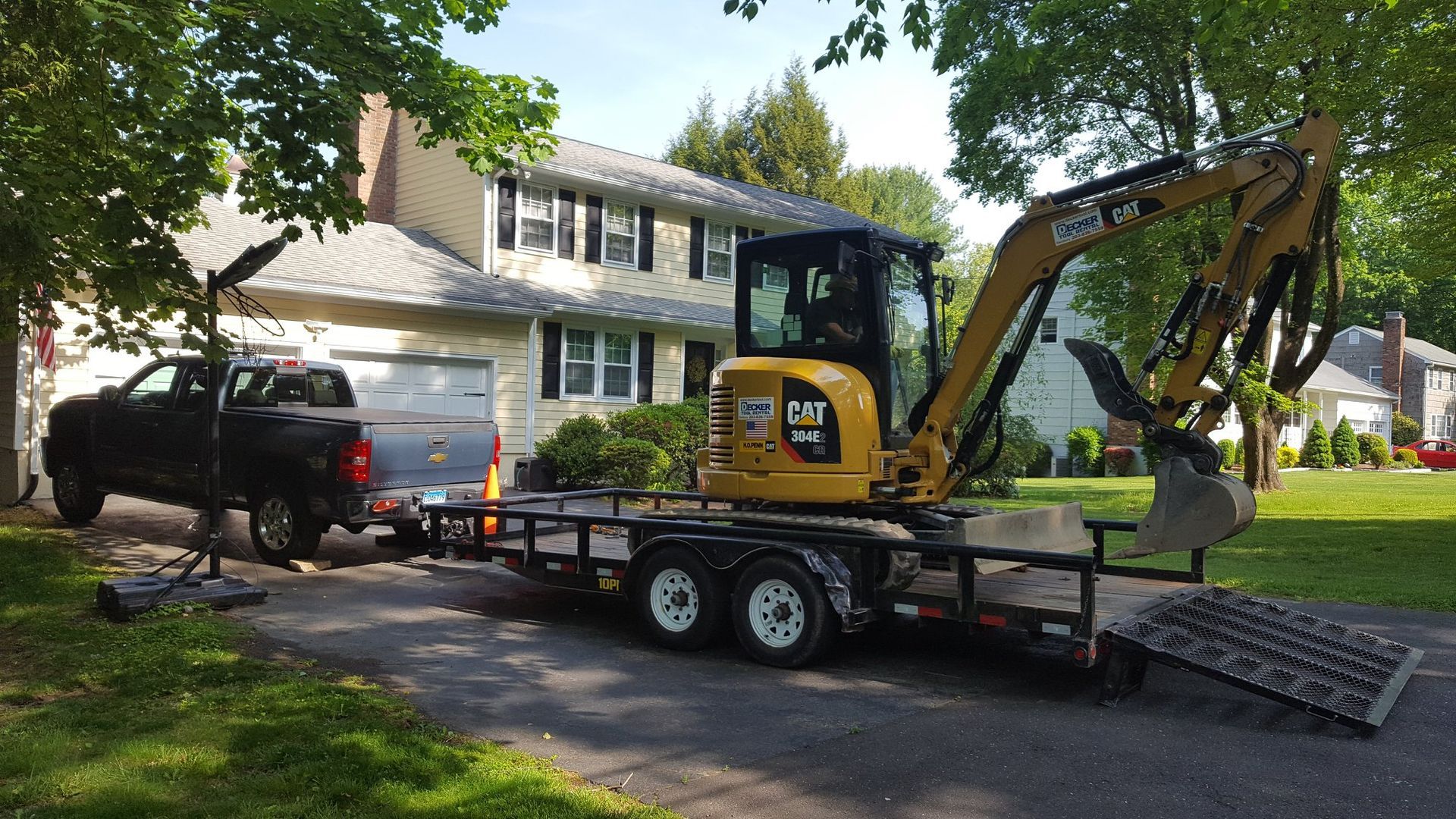 An excavator is on a trailer in front of a house.