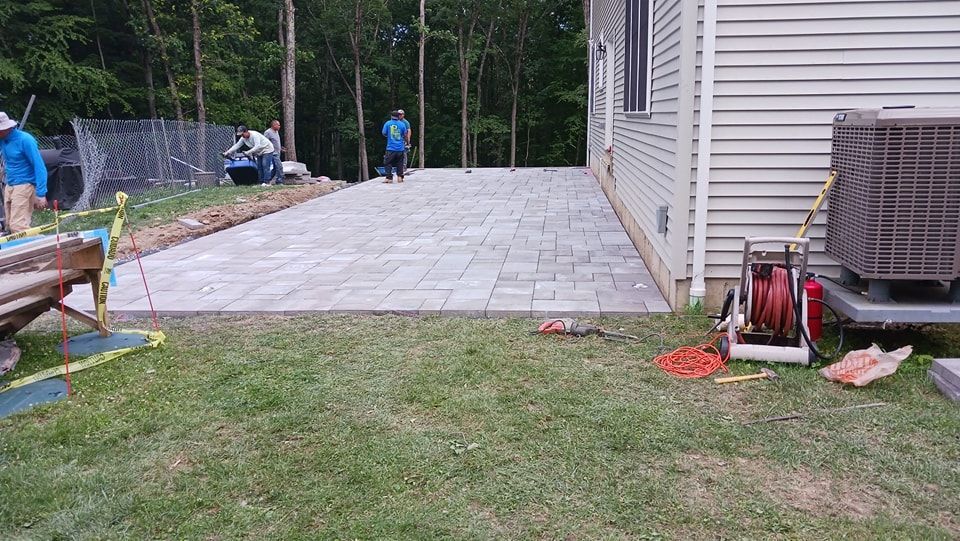A patio is being built in the backyard of a house.