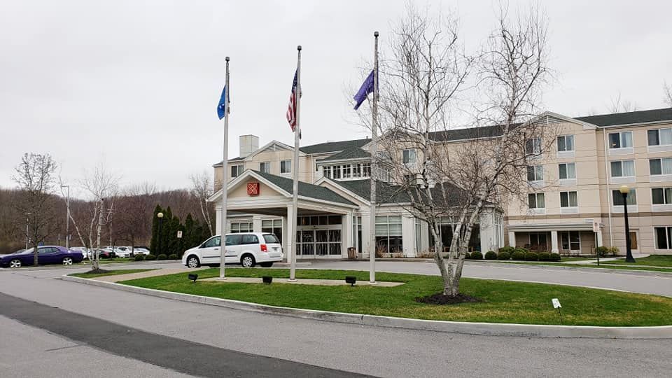 A white van is parked in front of a large building.