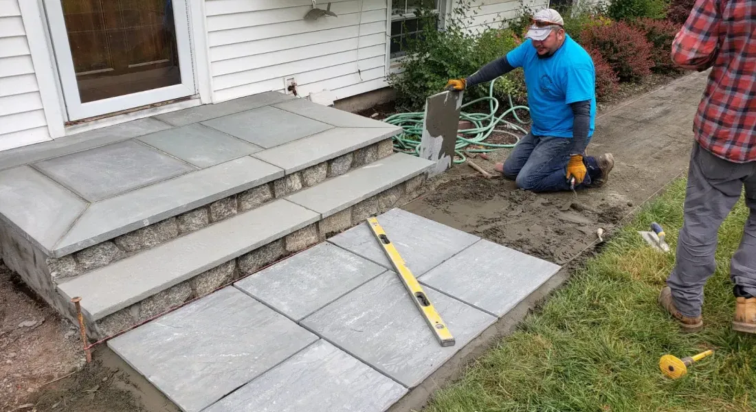 A man is kneeling down while using a shovel to build a walkway.